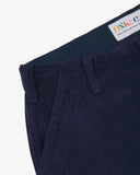 Close-up front view of left front pocket, belt loops, triple stitching, branding label and contrasting lining. Also a closer view of the organic, 11 wale corduroy in deep indigo.