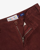 Close-up of Uskees deep wine berry corduroy trousers for men showing zip fly and button, as well as brand label details.