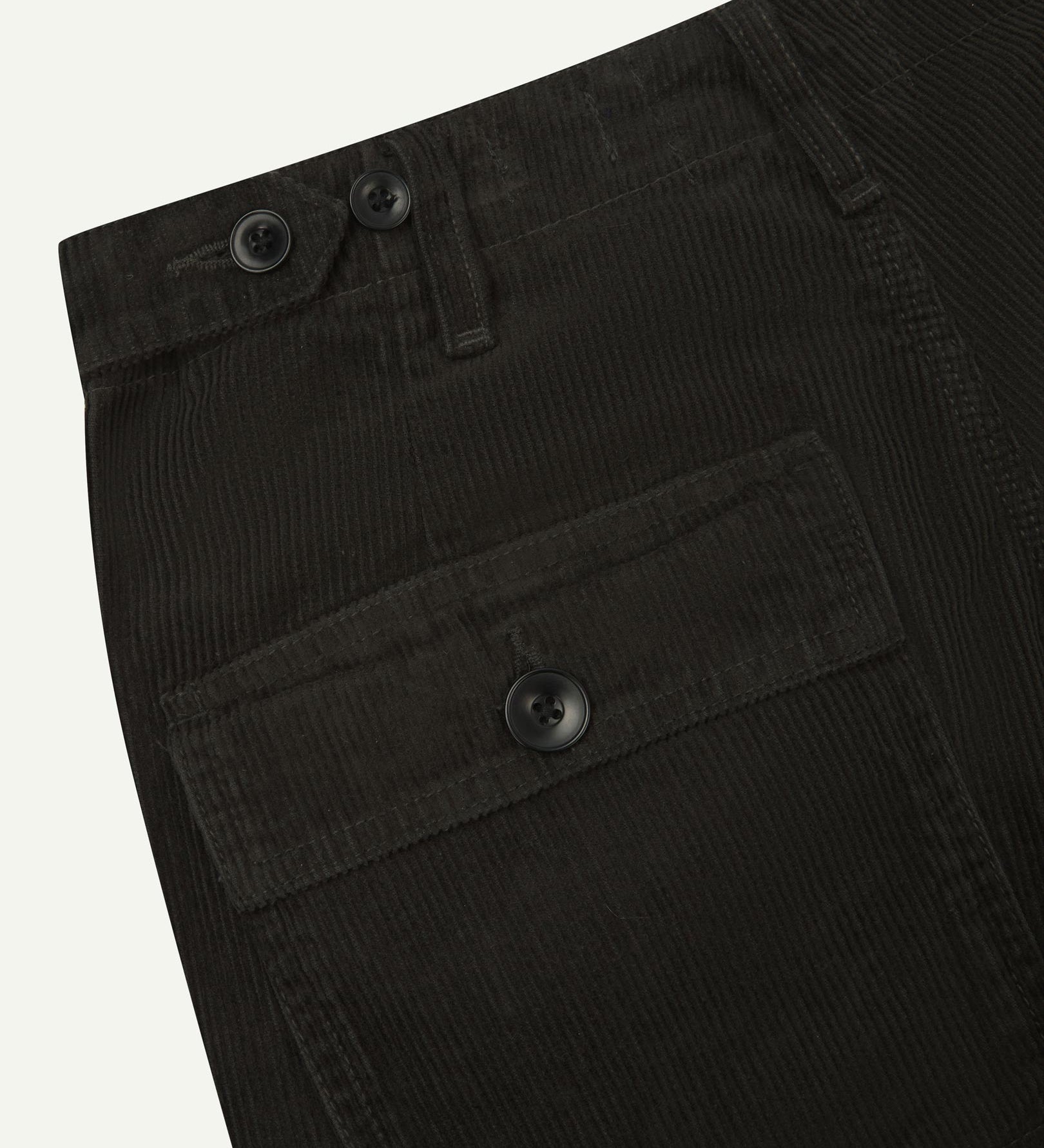 Close-up reverse view of Uskees faded black corduroy work pants with focus on left rear pocket, belt loops, triple stitching and adjustable button waist.