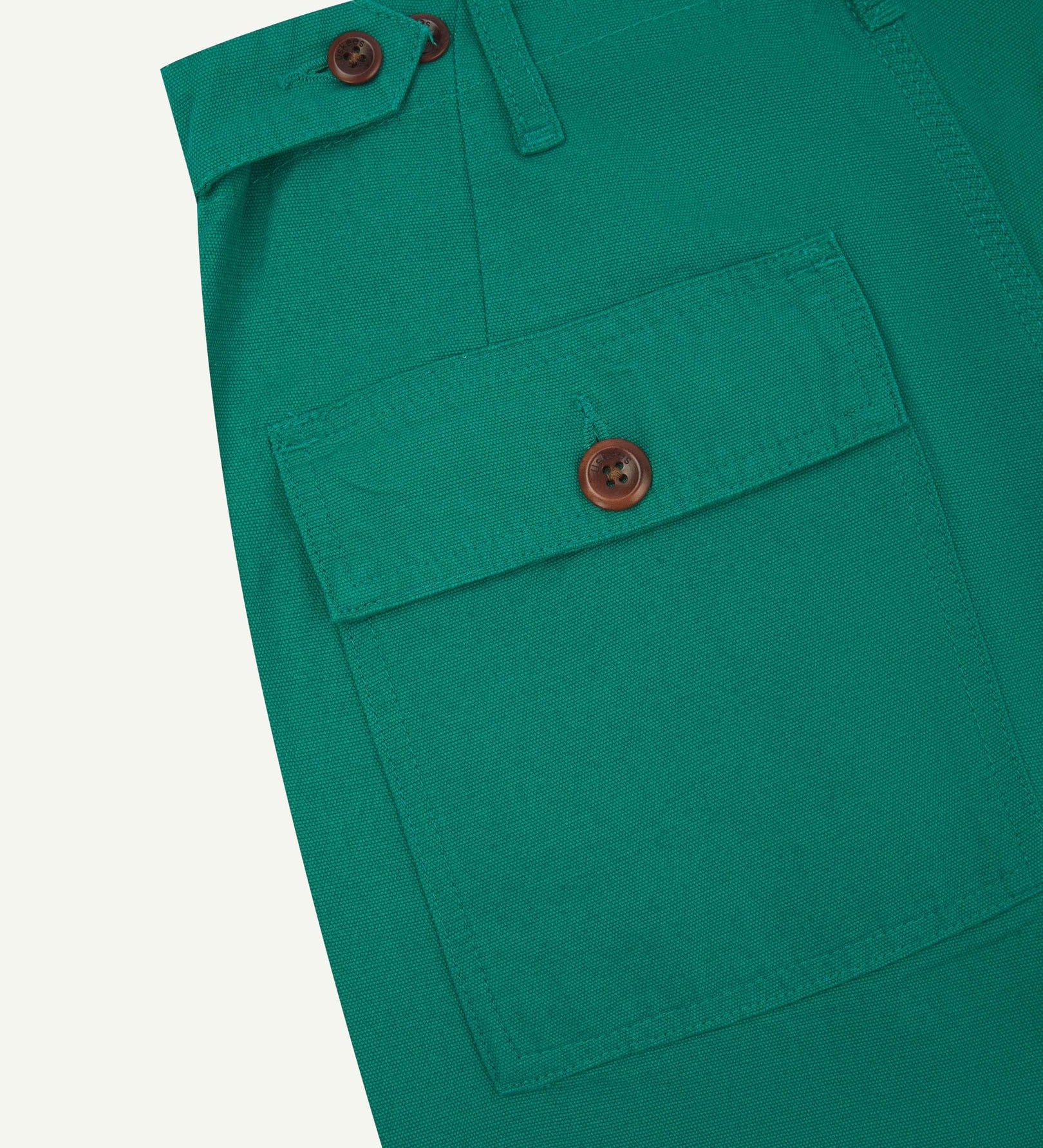 Close-up reverse view of Uskees foam green cotton work pants with focus on left rear pocket, belt loops, triple stitching and adjustable button waist.