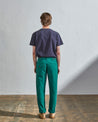 Full length back-view of model wearing bright turquoise, 'foam green' coloured organic cotton #5005 trousers with view of rear and cargo pockets. Paired with midnight blue t-shirt.
