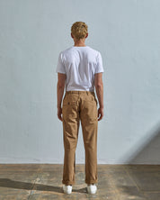 Full length back-view of model wearing khaki 5005 trousers with view of rear pockets and belt loops. Paired with plain white t-shirt.
