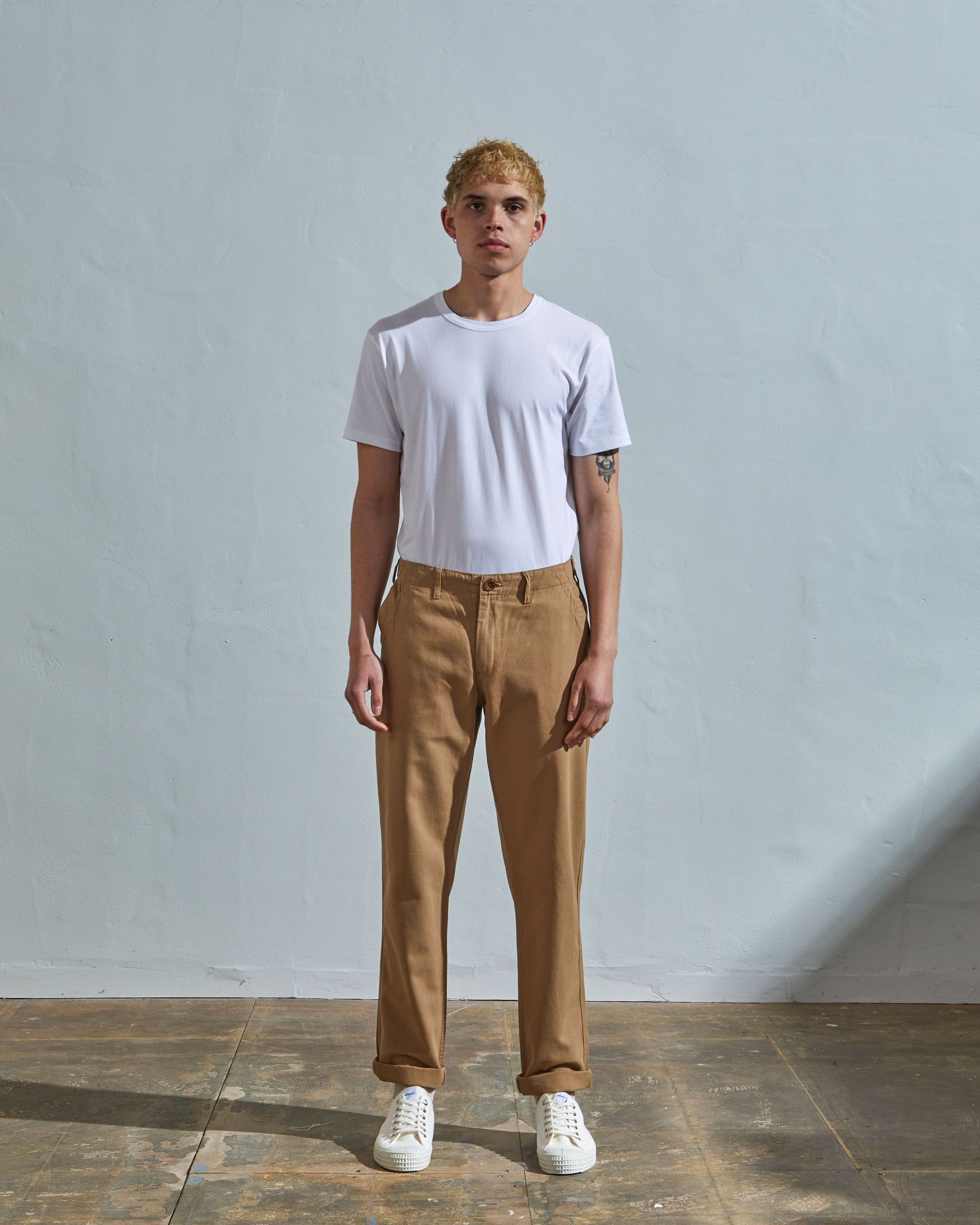 Full length front-view of model wearing khaki 5005 trousers with view of YKK zip fly and Corozo buttons. Paired with plain white t-shirt.