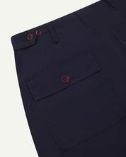 Close-up reverse view of Uskees midnight blue cotton work pants with focus on left rear pocket, belt loops, triple stitching and adjustable button waist.