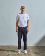 Full length back-view of model wearing midnight blue 5005 work trousers with view of rear pockets and belt loops. Paired with plain white Uskees t-shirt.