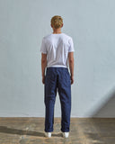 Full length back-view of model wearing navy blue 5005 trousers with view of rear pockets and belt loops. Paired with plain white t-shirt.