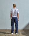 Full length back-view of model wearing navy blue 5005 trousers with view of rear pockets and belt loops. Paired with plain white t-shirt.