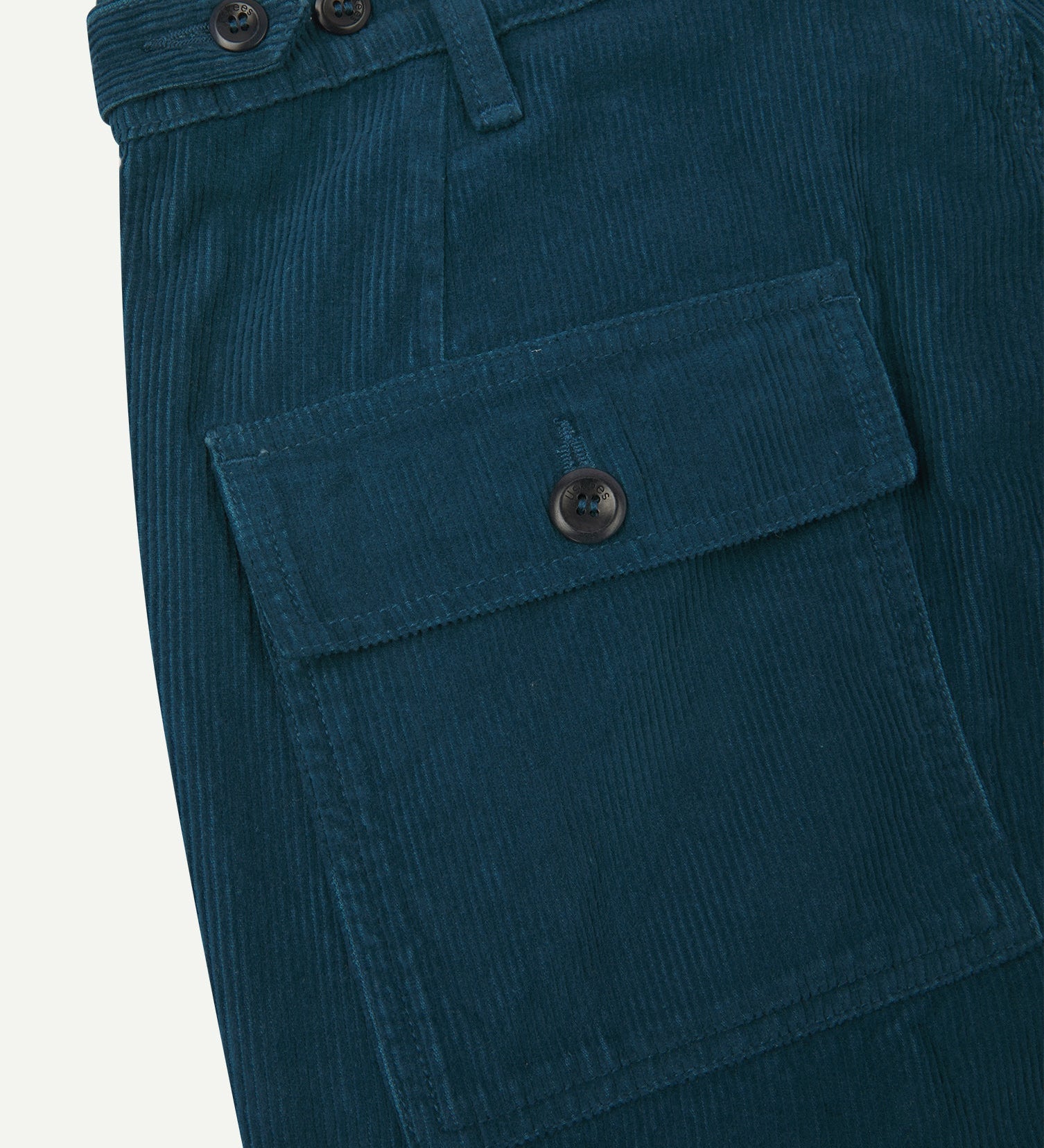 Close-up reverse view of Uskees petrol blue corduroy work pants with focus on left rear flap pocket, belt loops and adjustable button waist.