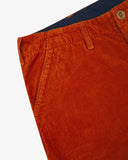 Close-up front view of left front pocket, belt loops, triple stitching, and contrasting lining. Also a closer view of the organic, 11 wale corduroy in rust-red.
