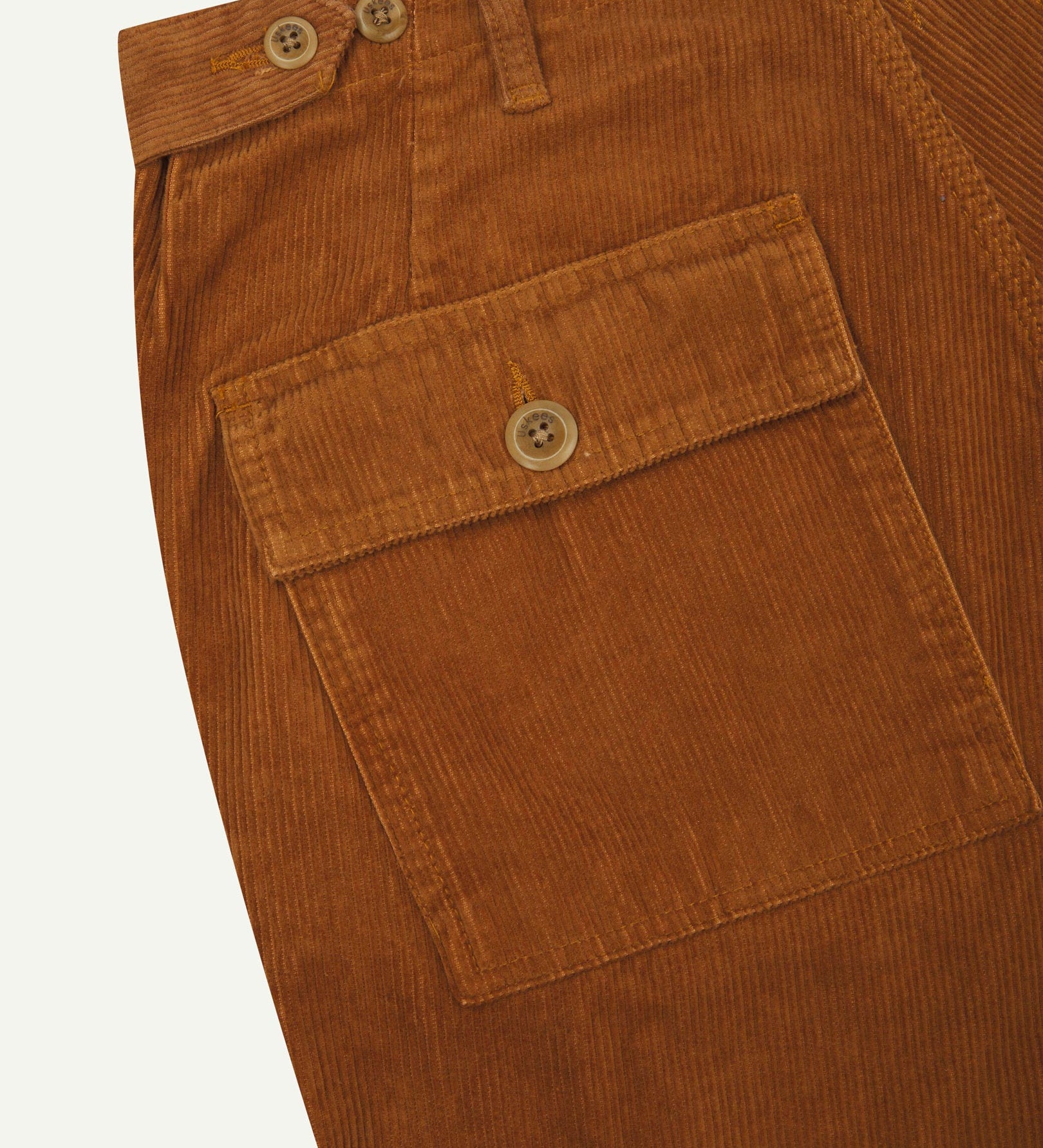 Close-up reverse view of Uskees tan corduroy work pants with focus on left rear pocket, belt loops, triple stitching and adjustable button waist.