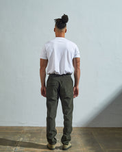 Full length back-view of model wearing vine green corduroy 5005 trousers with view of rear pockets and belt loops. Paired with plain white t-shirt.