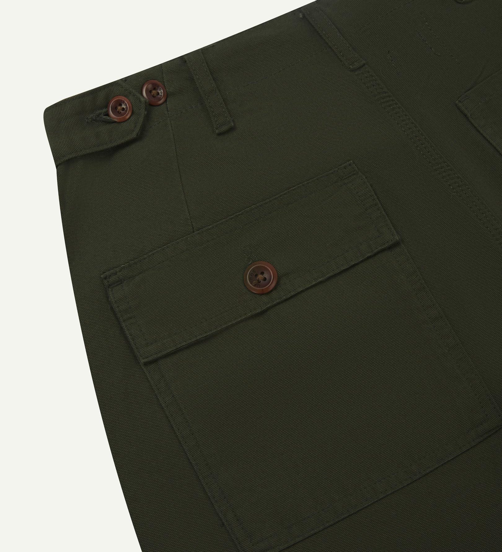 Close-up reverse view of Uskees vine green cotton work pants with focus on left rear pocket, belt loops, triple stitching and adjustable button waist.