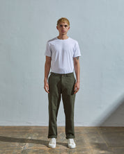 Full length front-view of model wearing vine green 5005 trousers with view of YKK zip fly and Corozo buttons. Paired with plain white t-shirt.