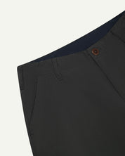Close up view of uskees #5005 men's trousers in dark grey showing lined waist, front pocket, button fastening and belt loops