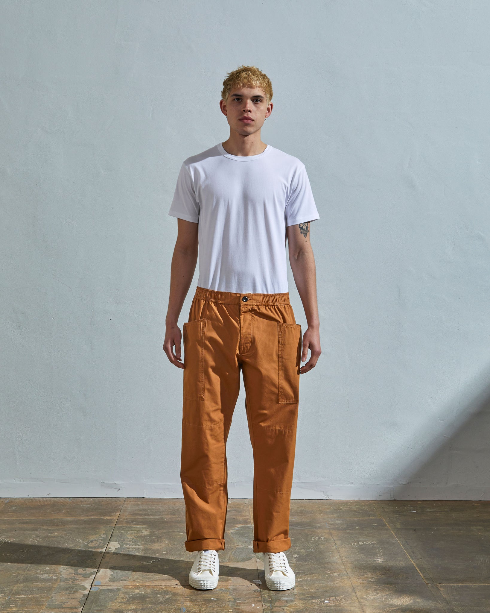 Full length front-view of model wearing pale brown light 160gsm cotton 5011 trousers with view of deep pockets and paired with plain white t-shirt.
