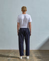 Full length back-view of model wearing midnight blue lightweight cotton 5011 trousers showing the relaxed, tapered fit on the leg and turn-ups.