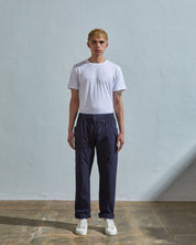 Full length front-view of model wearing midnight-blue light 160gsm cotton 5011 trousers with view of deep pockets and paired with plain white t-shirt.