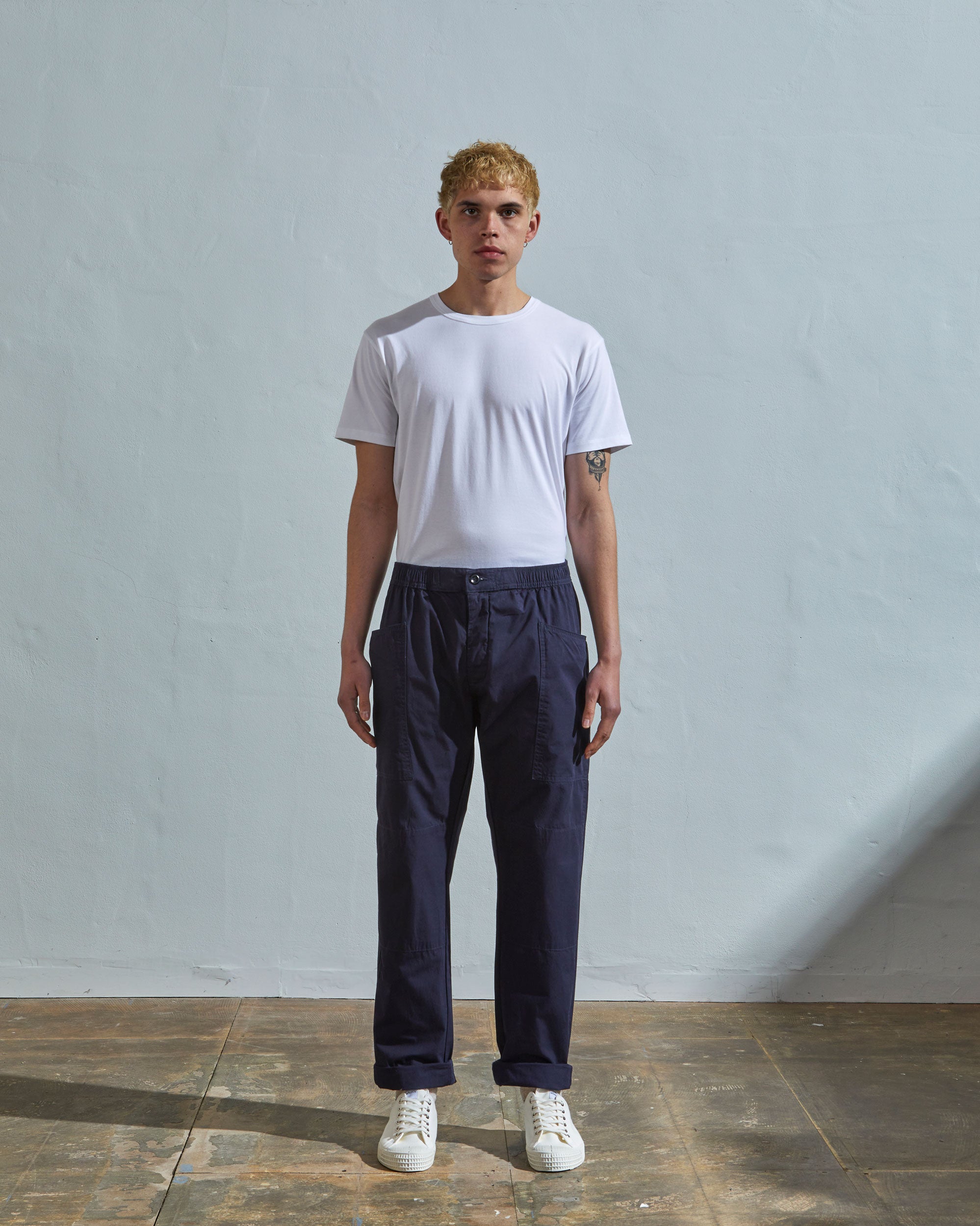 Full length front-view of model wearing midnight-blue light 160gsm cotton 5011 trousers with view of deep pockets and paired with plain white t-shirt.