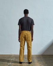 Full length reverse view of model wearing citronella-yellow corduroy 5012 trousers with view of straight leg fit, rear pockets and belt loops.