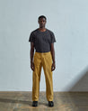 Full length front-view of model wearing citronella-yellow corduroy 5012 trousers with view of straight leg silhouette and Corozo buttons. Paired with faded black t-shirt.