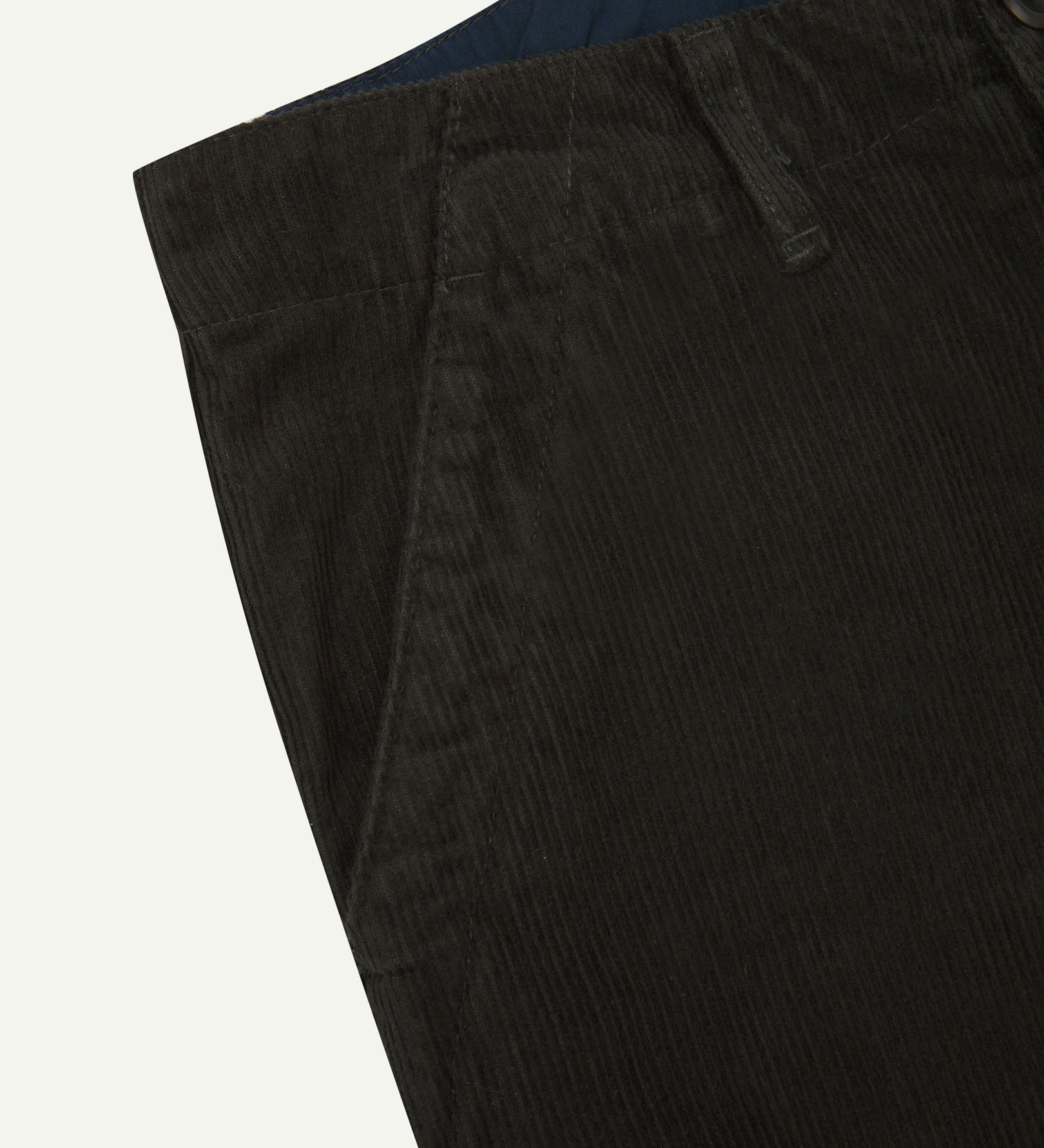 Close up front view of Uskees corduroy pants showing contract coloured inside waistband, front pockets and corozo button.