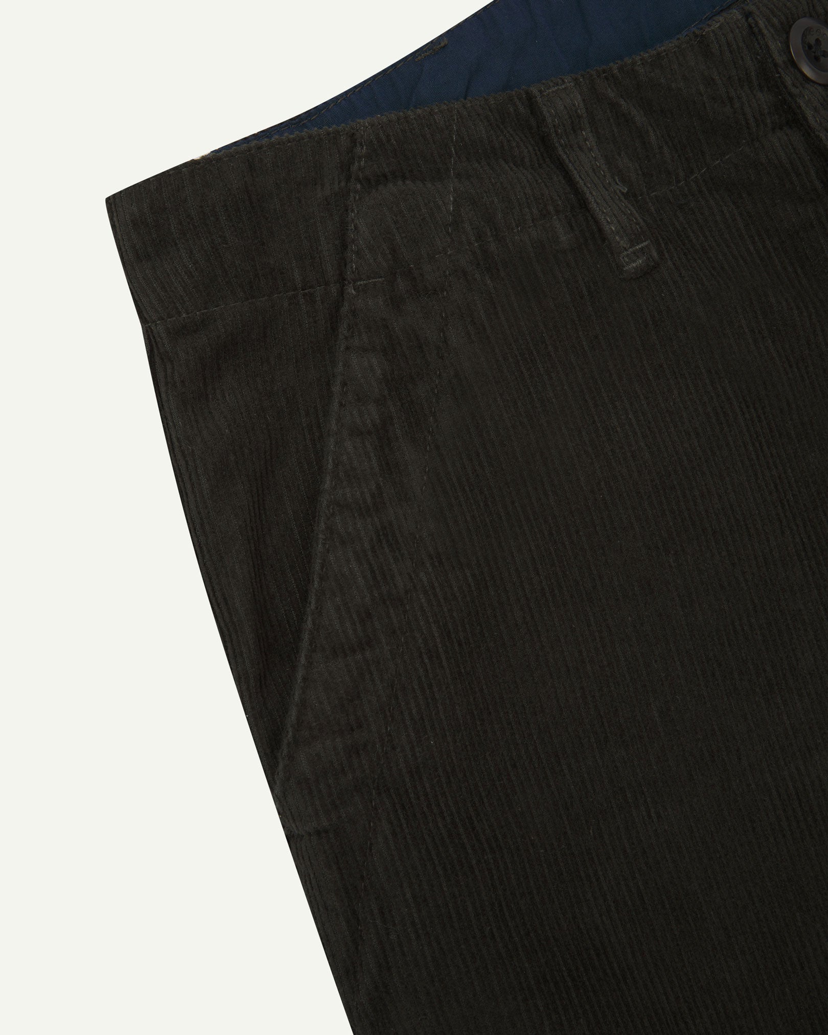 Close up front view of Uskees corduroy pants showing contract coloured inside waistband, front pockets and corozo button.