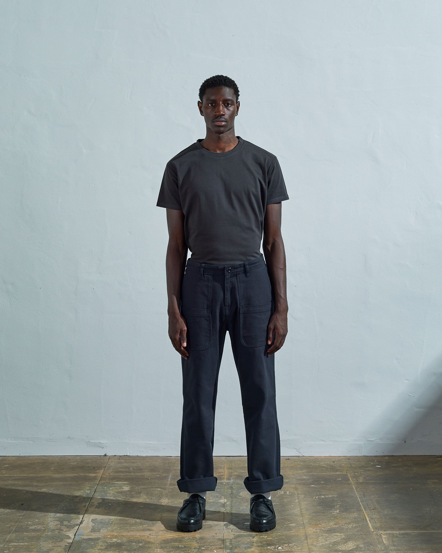 Full-length front view of model wearing #5013 drill commuter pants in blueberry with turn-ups, paired with Uskees faded black tee.