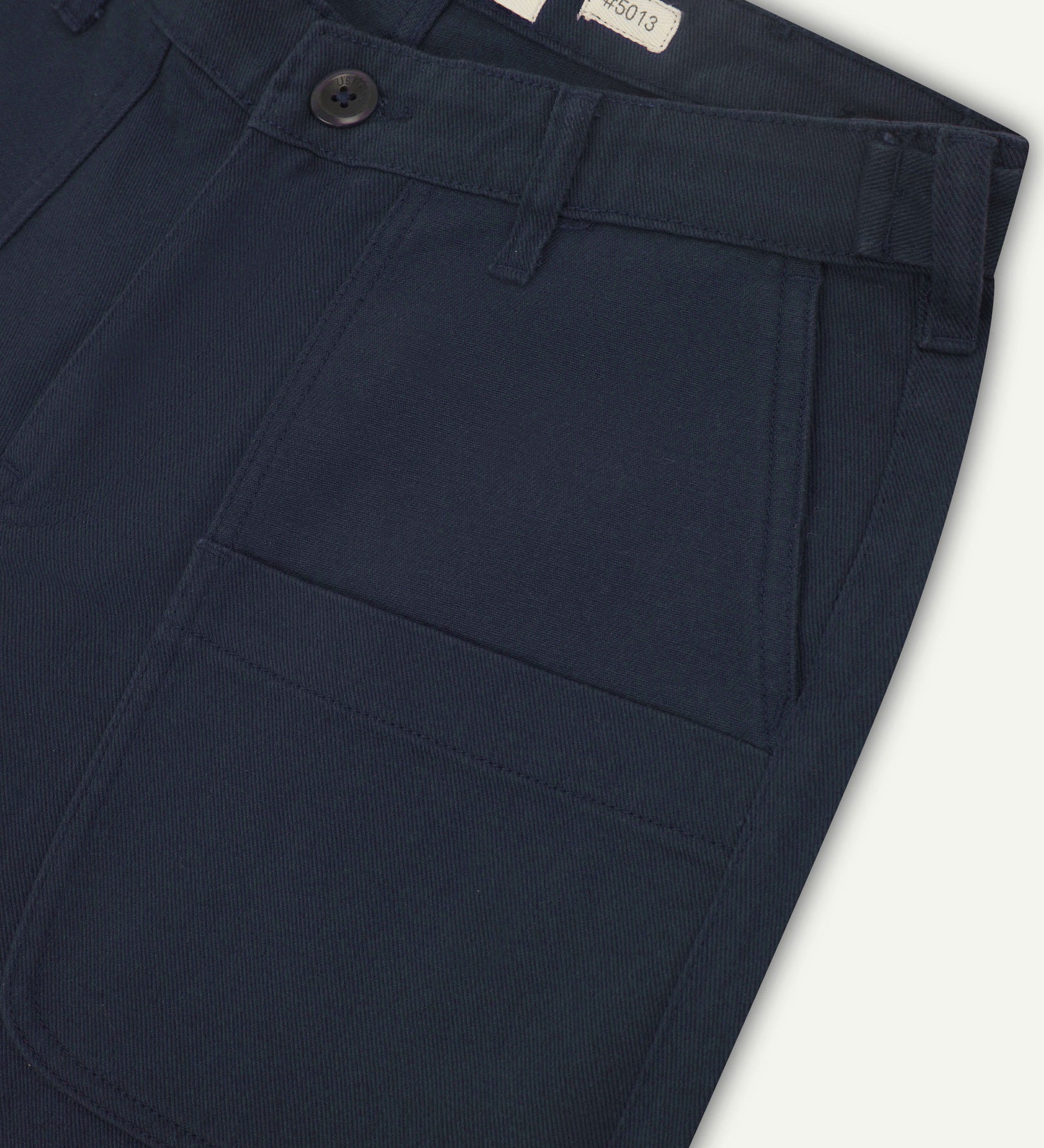 Front close-up of 5013 Uskees drill straight leg pants in dark blue, with focus on front pockets, layered pockets, belt loops waistband and Uskees branding label.