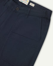 Front close-up of 5013 Uskees drill straight leg pants in dark blue, with focus on front pockets, layered pockets, belt loops waistband and Uskees branding label.