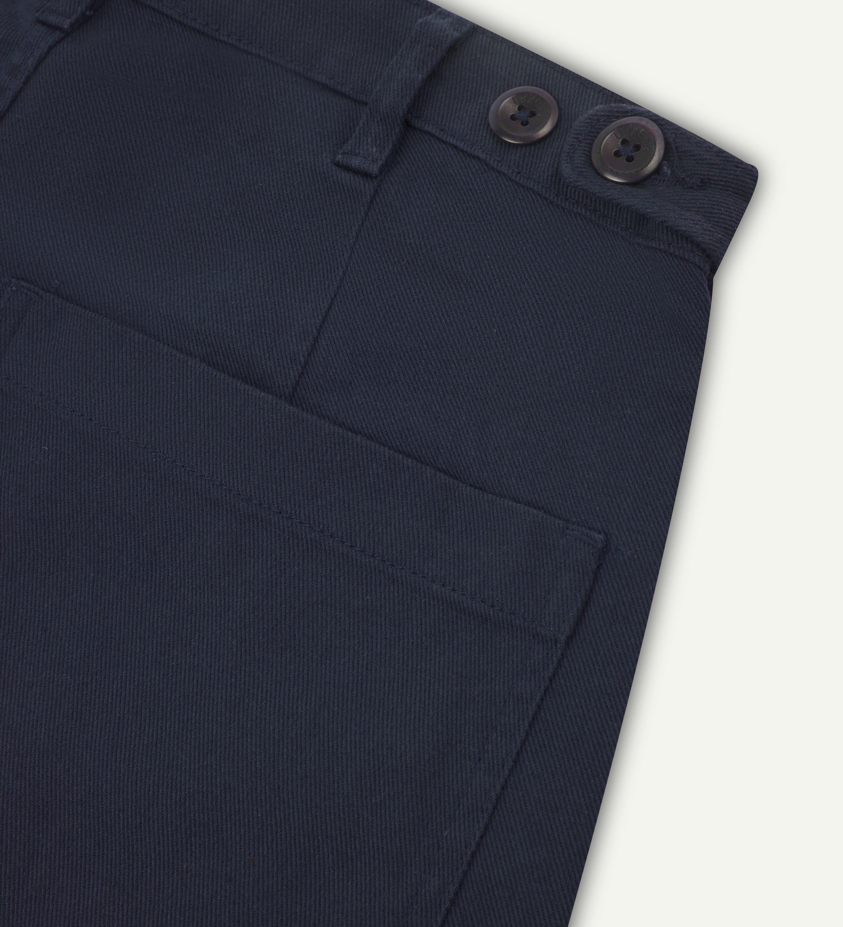 Close up shot of dark blue drill trousers from uskees showing back pocket and waist band button adjusters