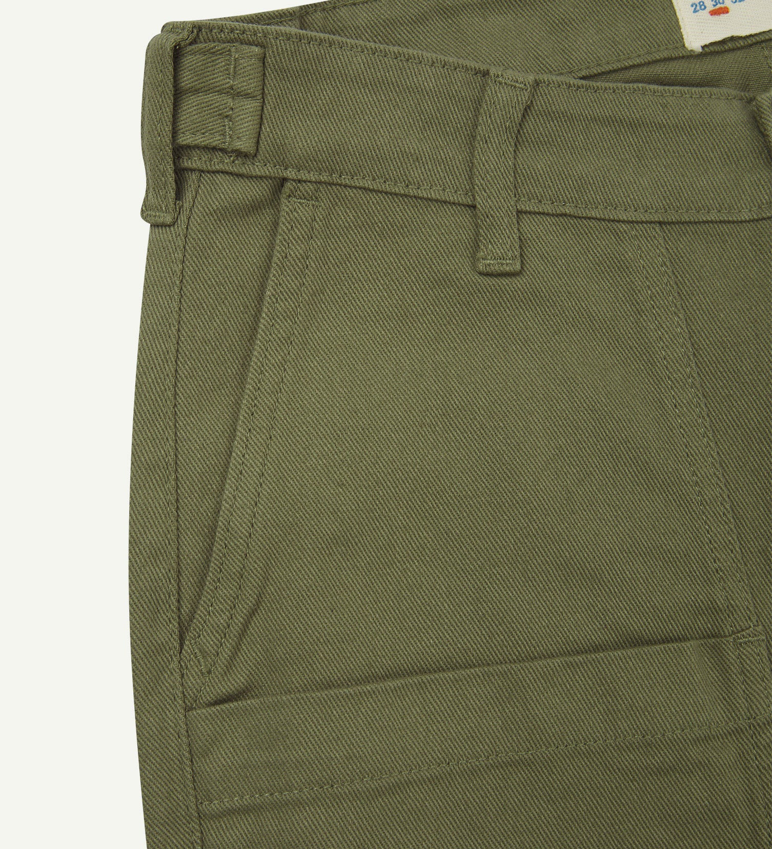 Front close-up of 5013 Uskees drill straight leg pants in moss green, with focus on front pockets, layered pockets, belt loops waistband and Uskees branding label.