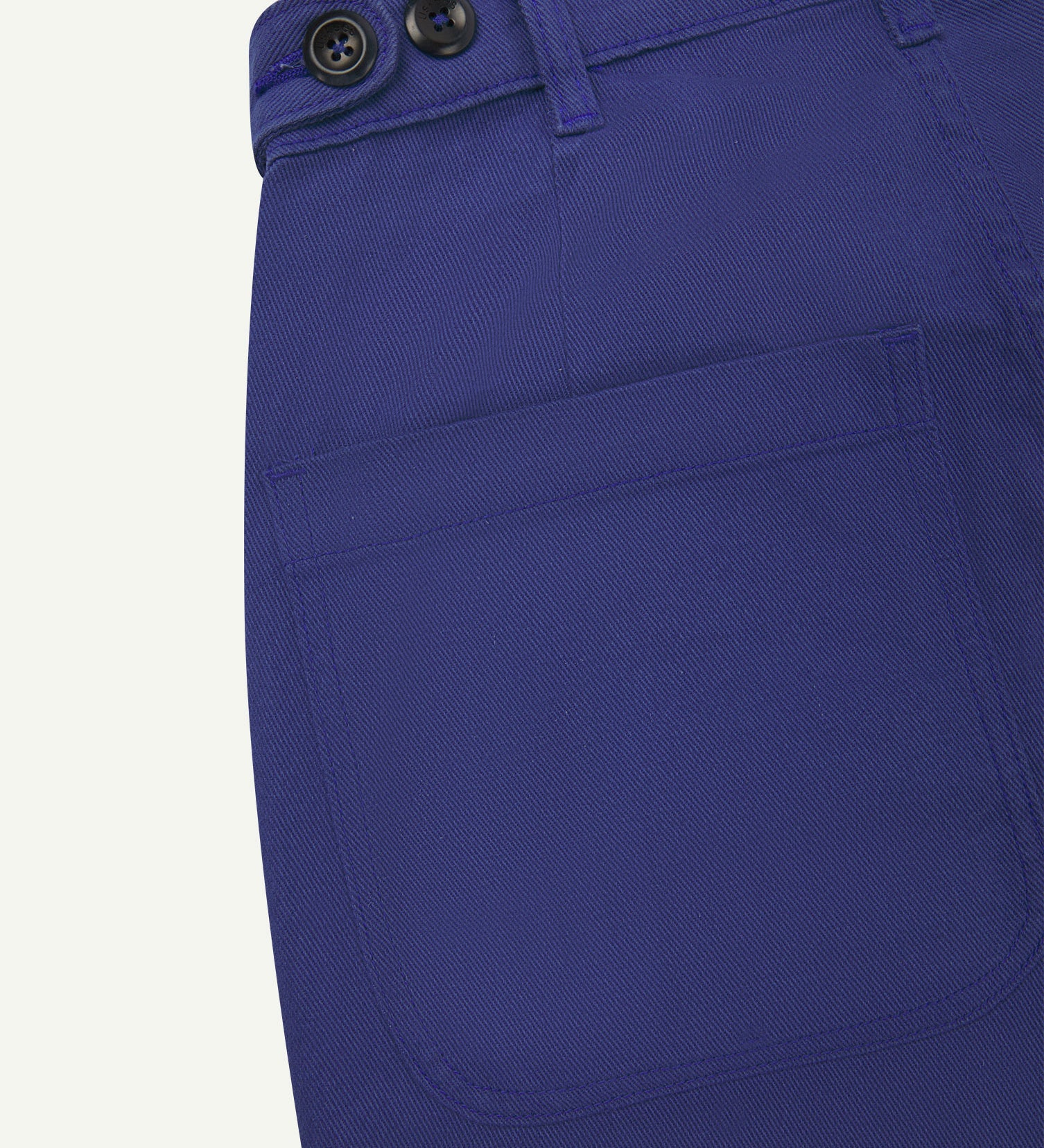 Back close-up of 5013 Uskees drill straight leg pants in ultra blue, with focus on left rear pocket, belt loops and adjustable waistband with corozo buttons.