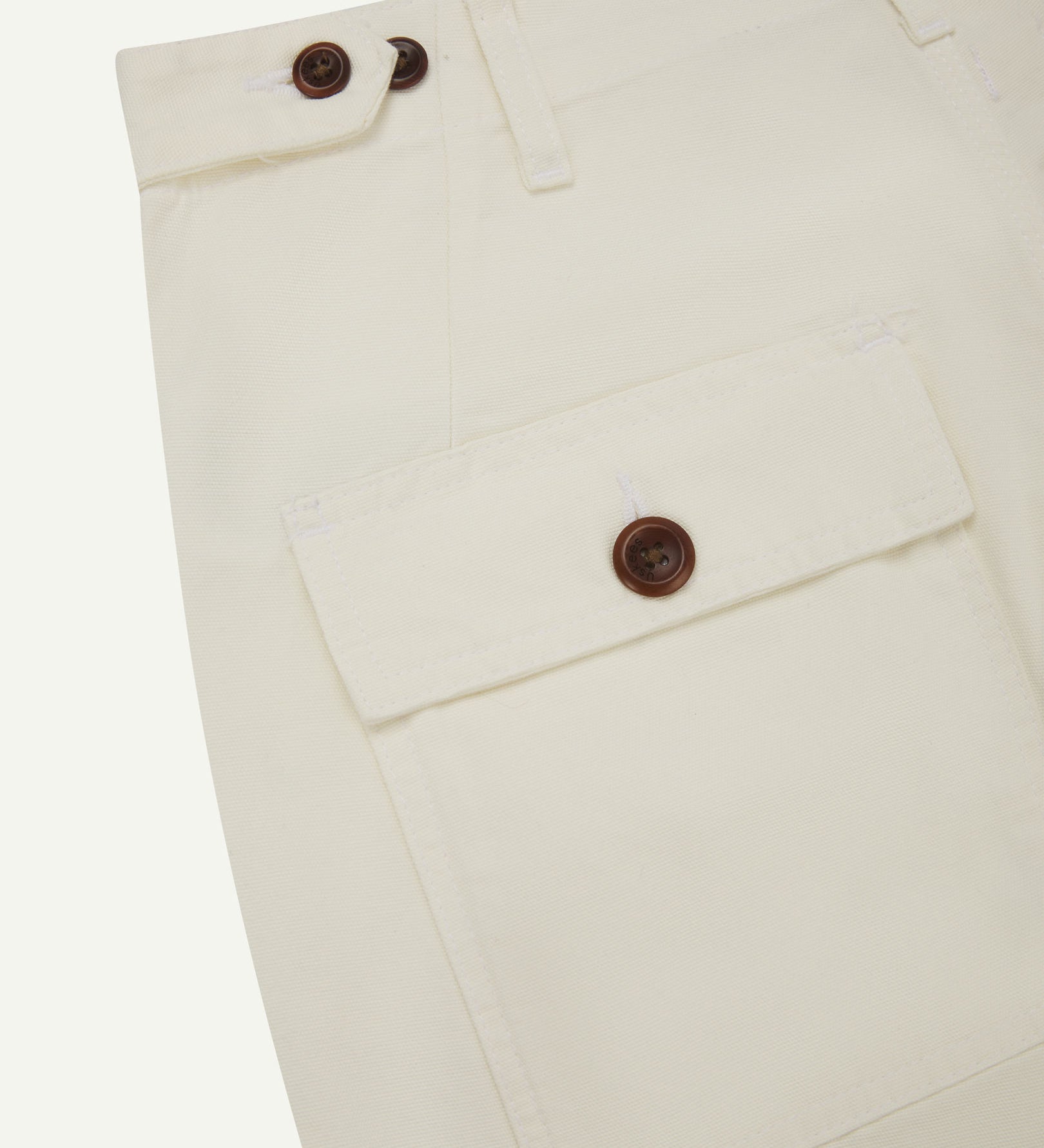 Reverse close-up of cargo pocket detailing and corozo buttons of the cream 5014 pants from Uskees.