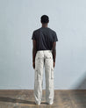 Full length back-view of model wearing cream organic cotton #5014 trousers with view of rear and cargo pockets. Paired with faded black Uskees t-shirt.