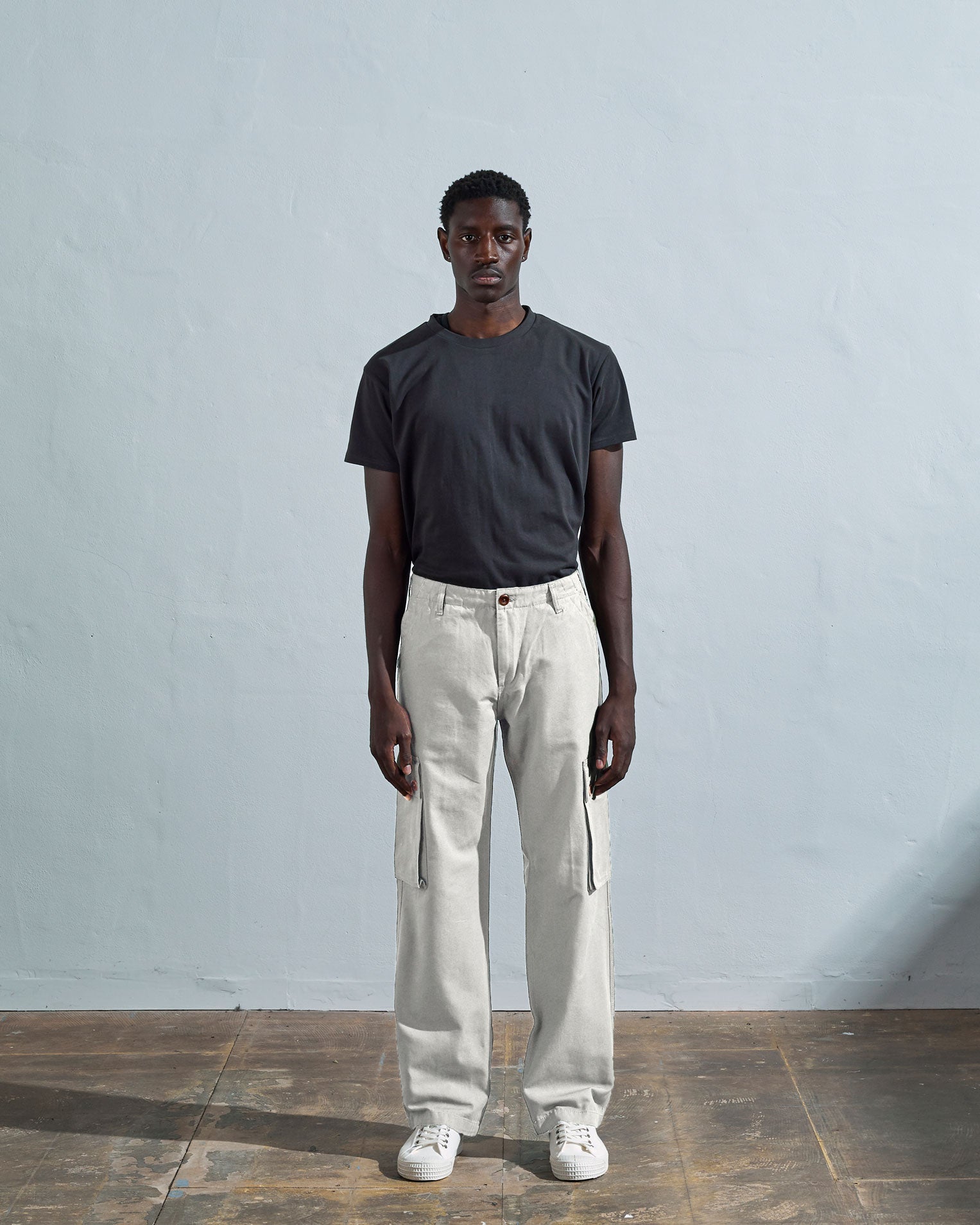Full length front-view of model wearing cream cotton 5014 trousers with view of belt loops, cargo pockets and Corozo buttons.