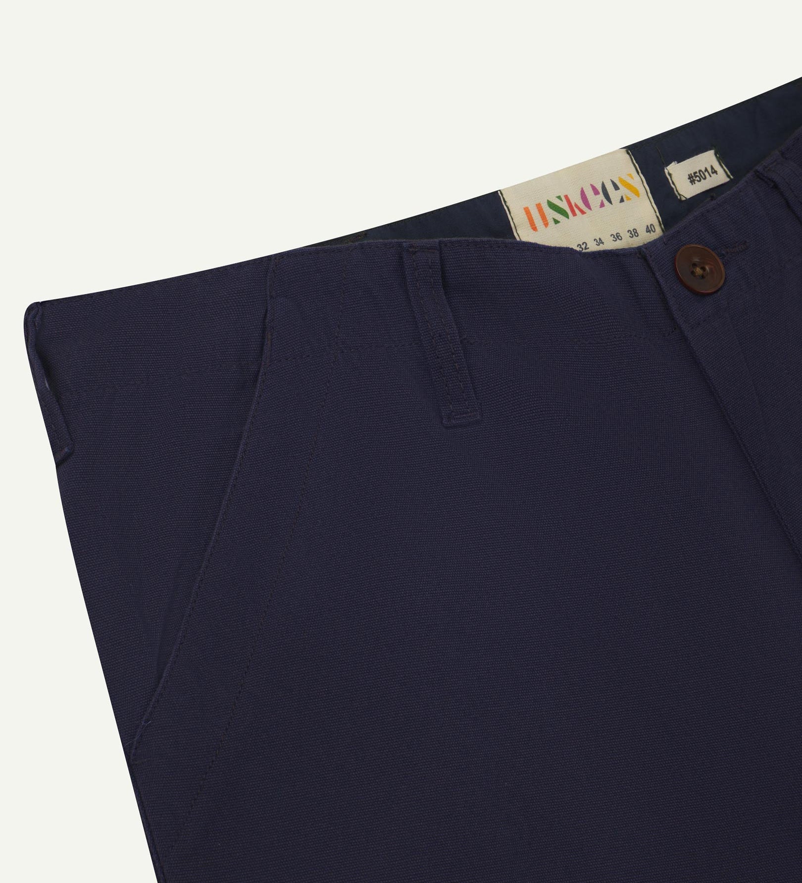 Front close-up of midnight blue 5014 pants from Uskees with focus on contrasting waist lining fabric, side pockets and zip fly.