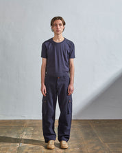 Full length front-view of model wearing midnight blue cotton 5014 trousers with view of belt loops, cargo pockets and Corozo buttons. Paired with matching t-shirt.