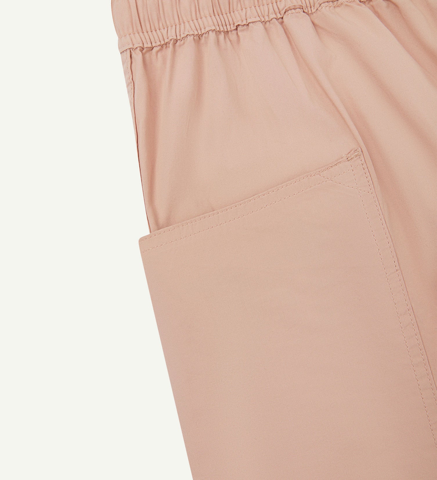 Close-up of the left pocket and stitching of the lightweight organic dusty pink-green cotton shorts.