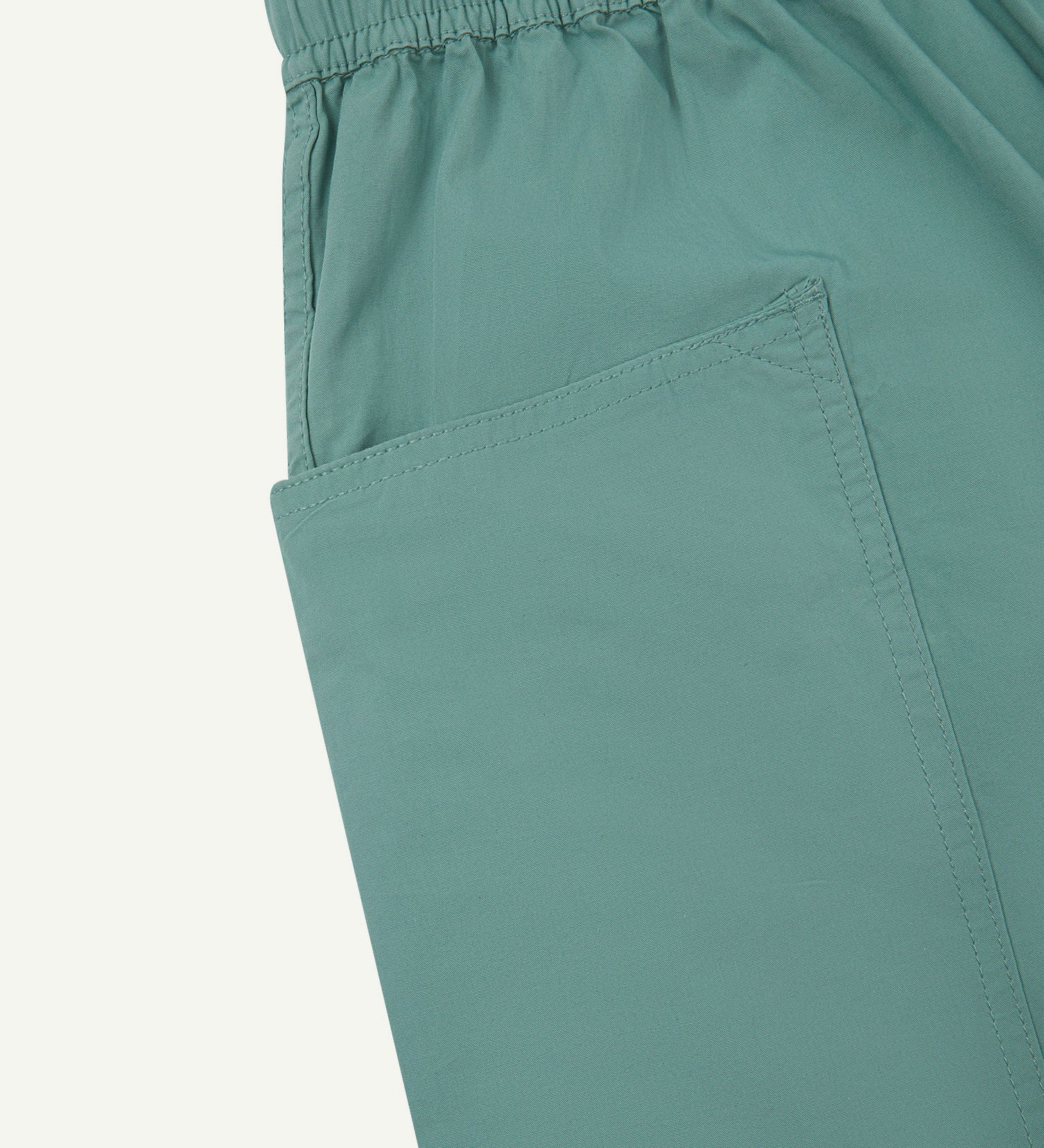 Close-up of the left pocket and stitching of the lightweight organic eucalyptus-green-green cotton shorts.