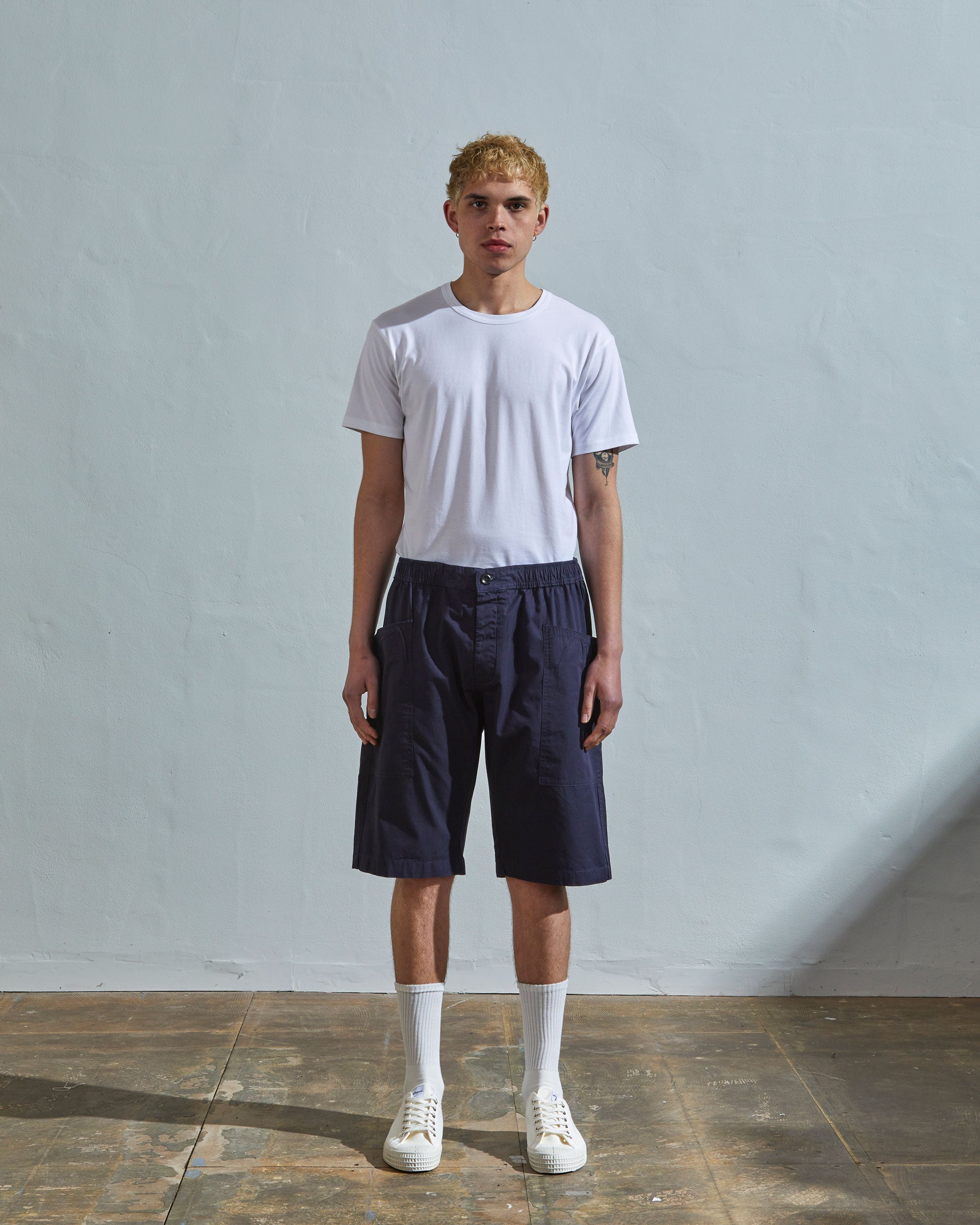 Front view of model wearing midnight blue organic cotton #5015 lightweight shorts by Uskees. Paired with simple white t-shirt.