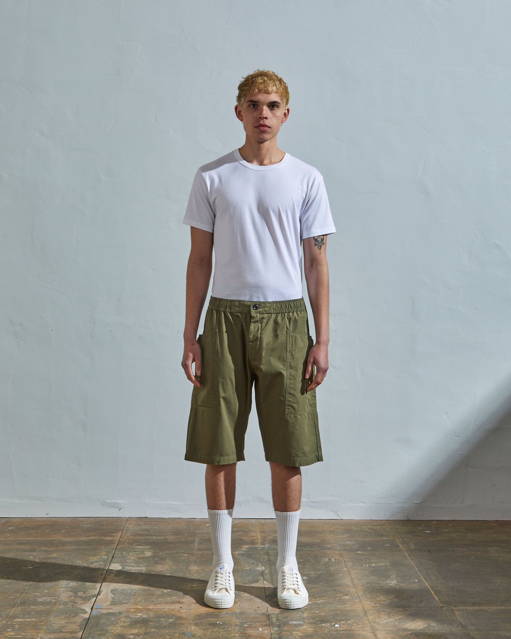 Front view of model wearing olive organic cotton #5015 lightweight shorts by Uskees. Paired with simple white t-shirt.