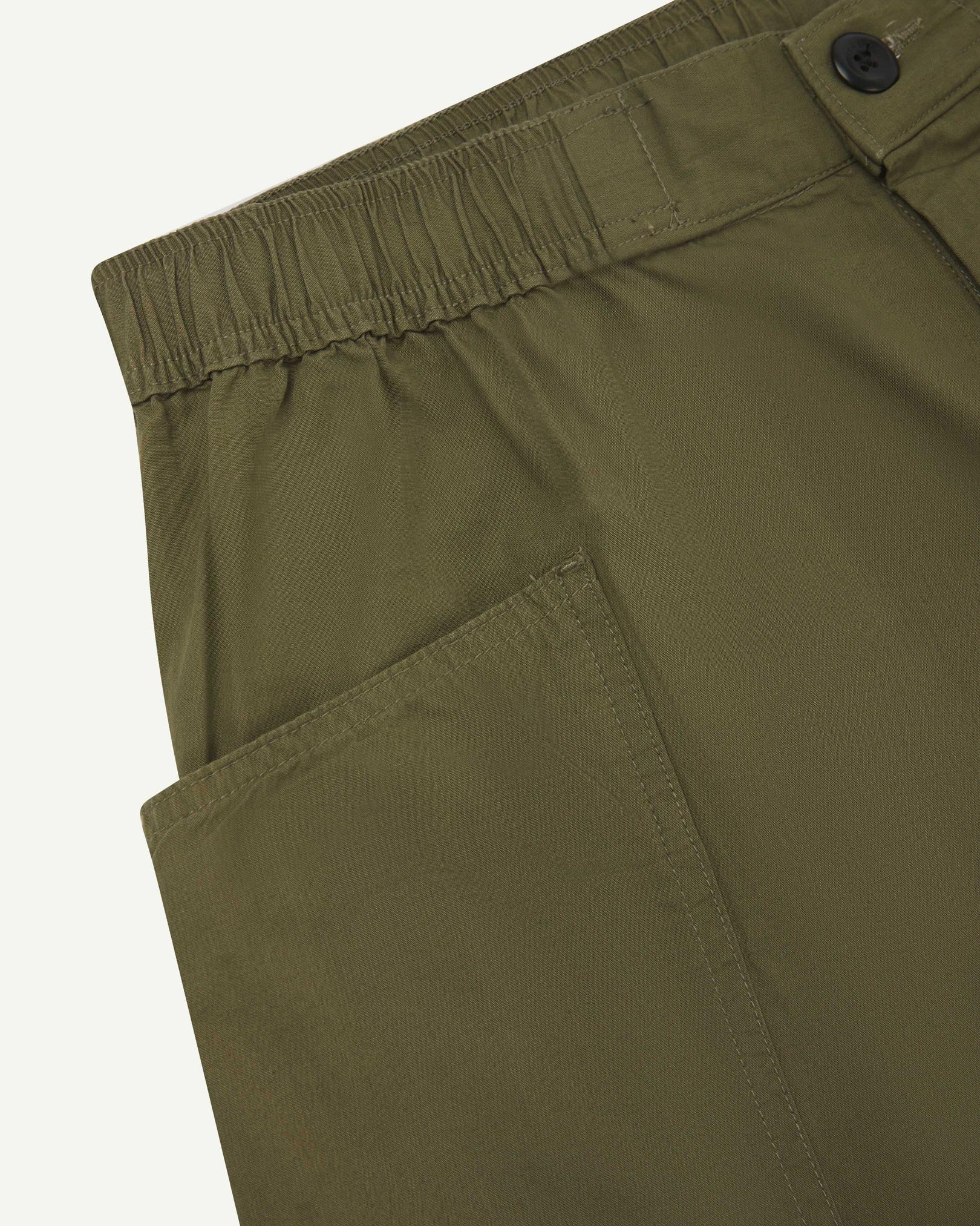 Close-up of the left pocket and stitching of the lightweight organic olive-green-green cotton shorts.