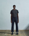 Full-length front view of model wearing #5016 drill commuter pants in blueberry with turn-ups, paired with Uskees faded black tee.