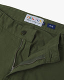 Close up view of 5016 Uskees men's organic twill coriander green 'commuter' trousers showing the zip and button fly and brand label.