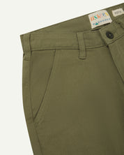 Close-up front view of the left-front pocket, belt loops and Corozo button of moss green heavyweight drill pants.