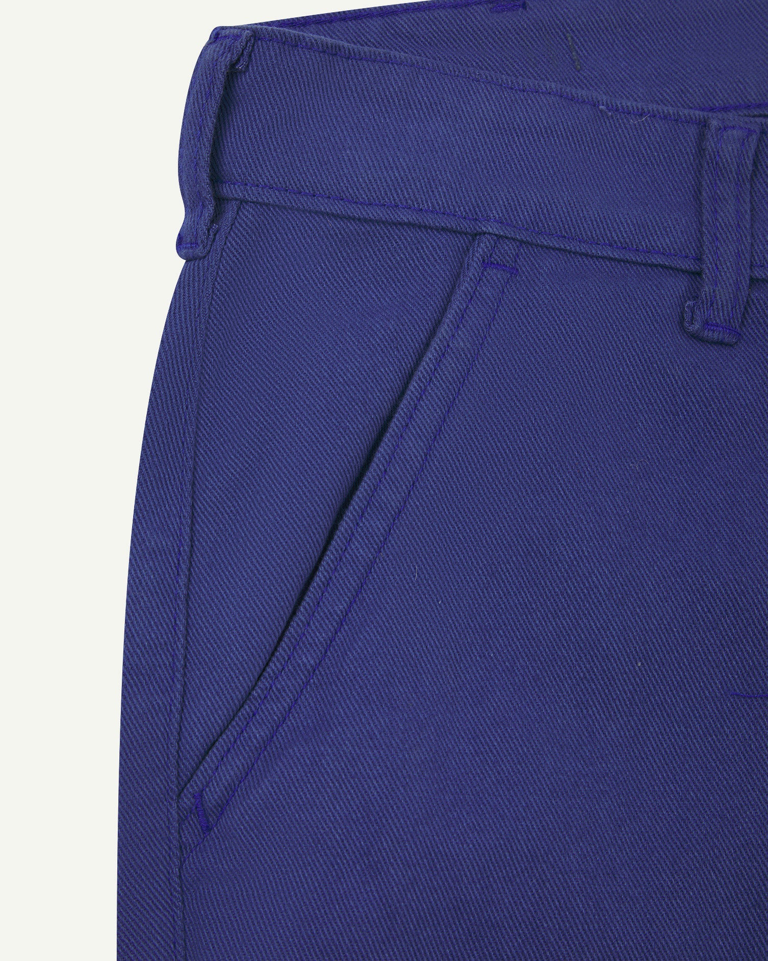 Close-up front view of the left-front pocket, belt loops and Corozo button of ultra-blue heavyweight drill pants.