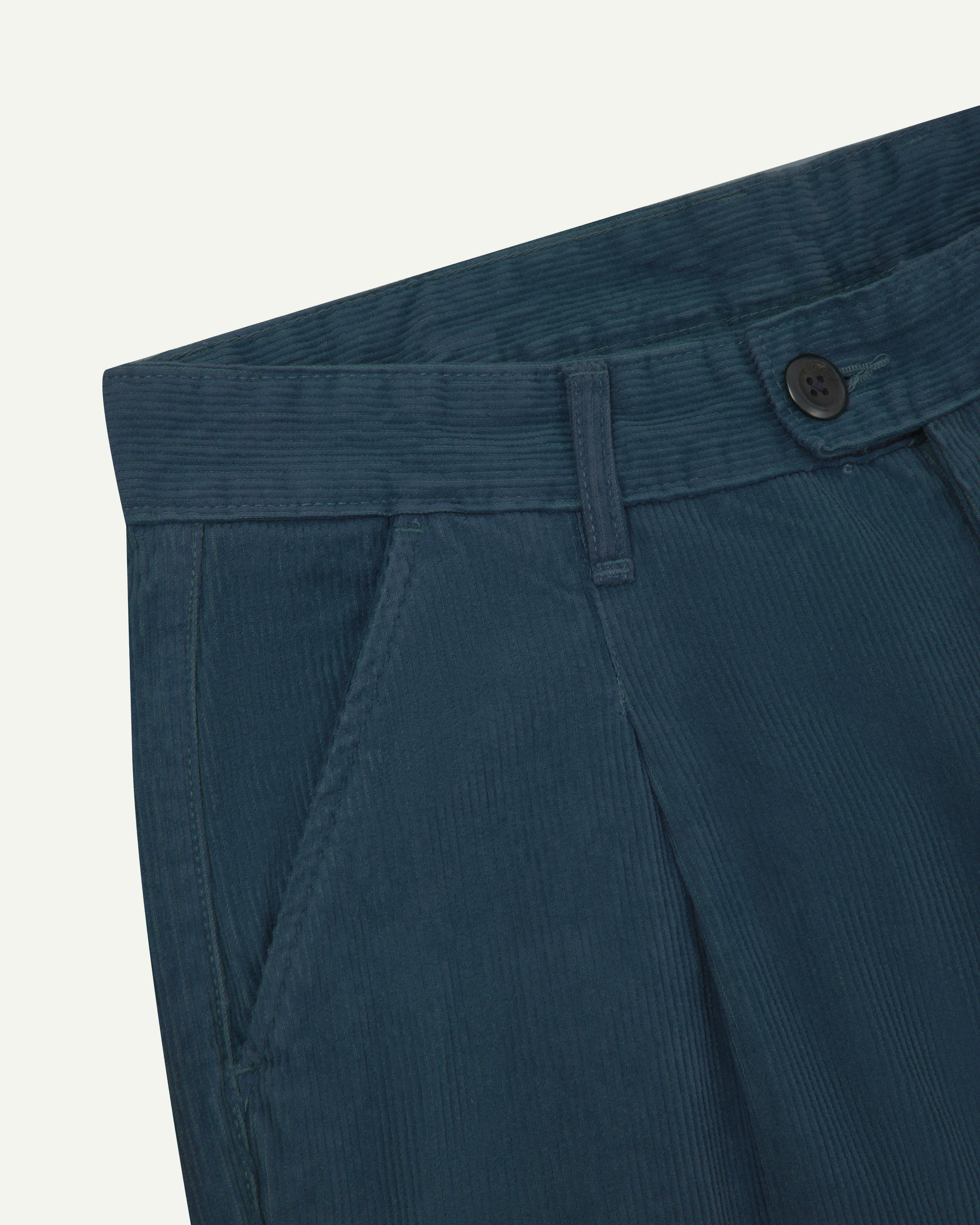 Close up of Uskees cord boat pants in petrol blue showing belt loops and Corozo button fastening.