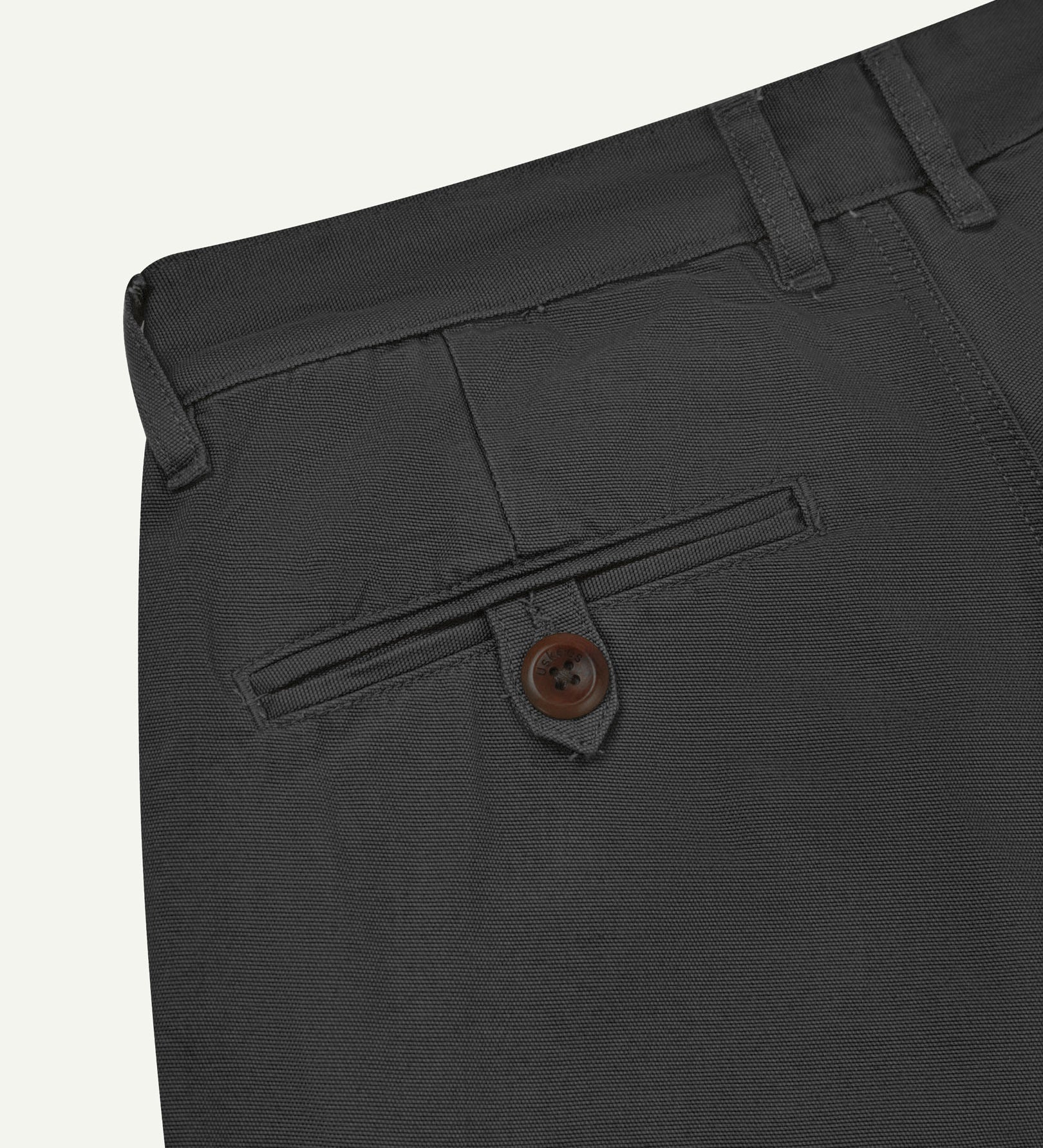 Back close-up view of 5018 Uskees men's organic mid-weight cotton boat trousers in acid charcoal grey showing belt loops and buttoned back pocket.