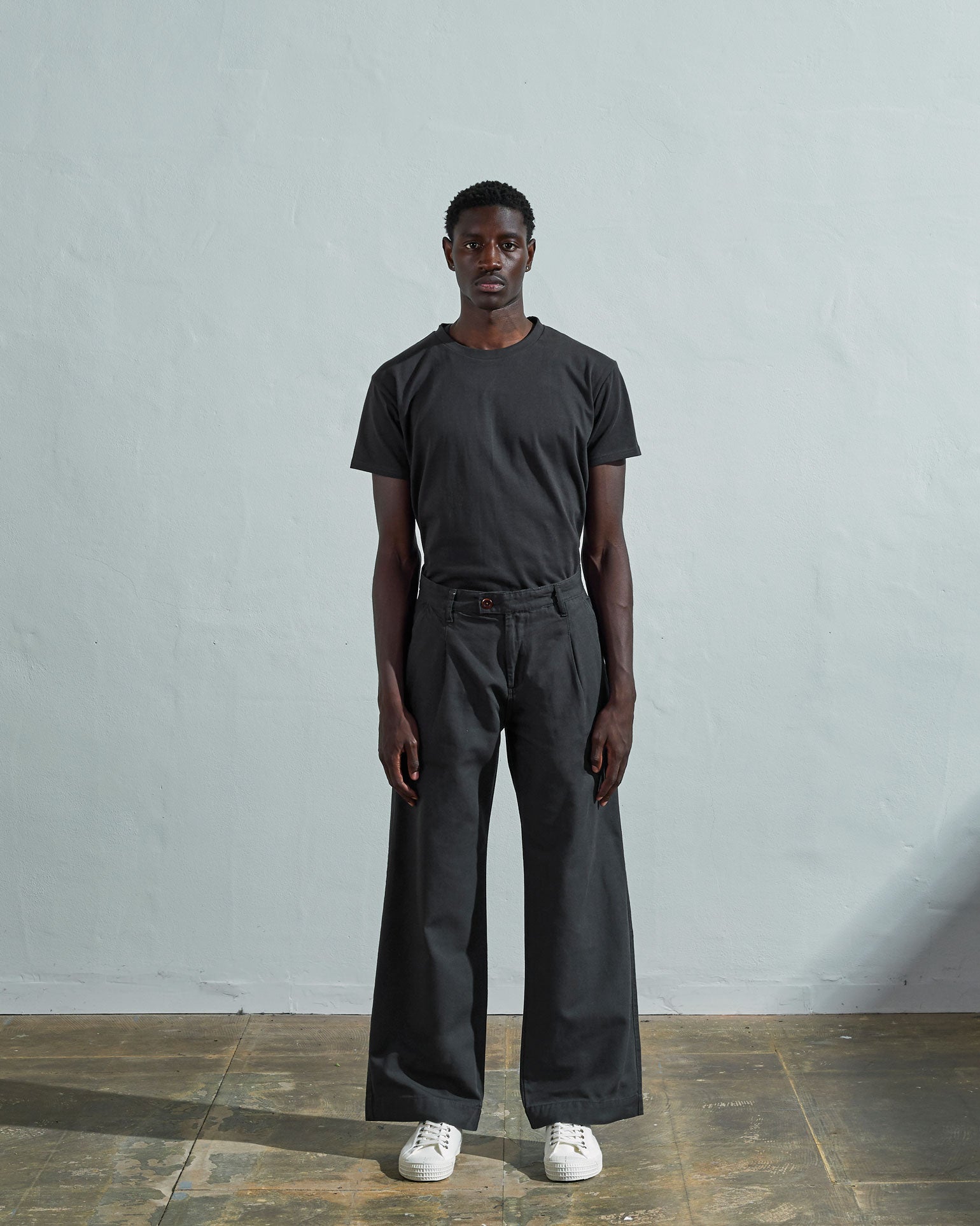 Full-length front view of model wearing Uskees #5018, charcoal-grey mid-weight cotton boat pants paired with faded black t-shirt.