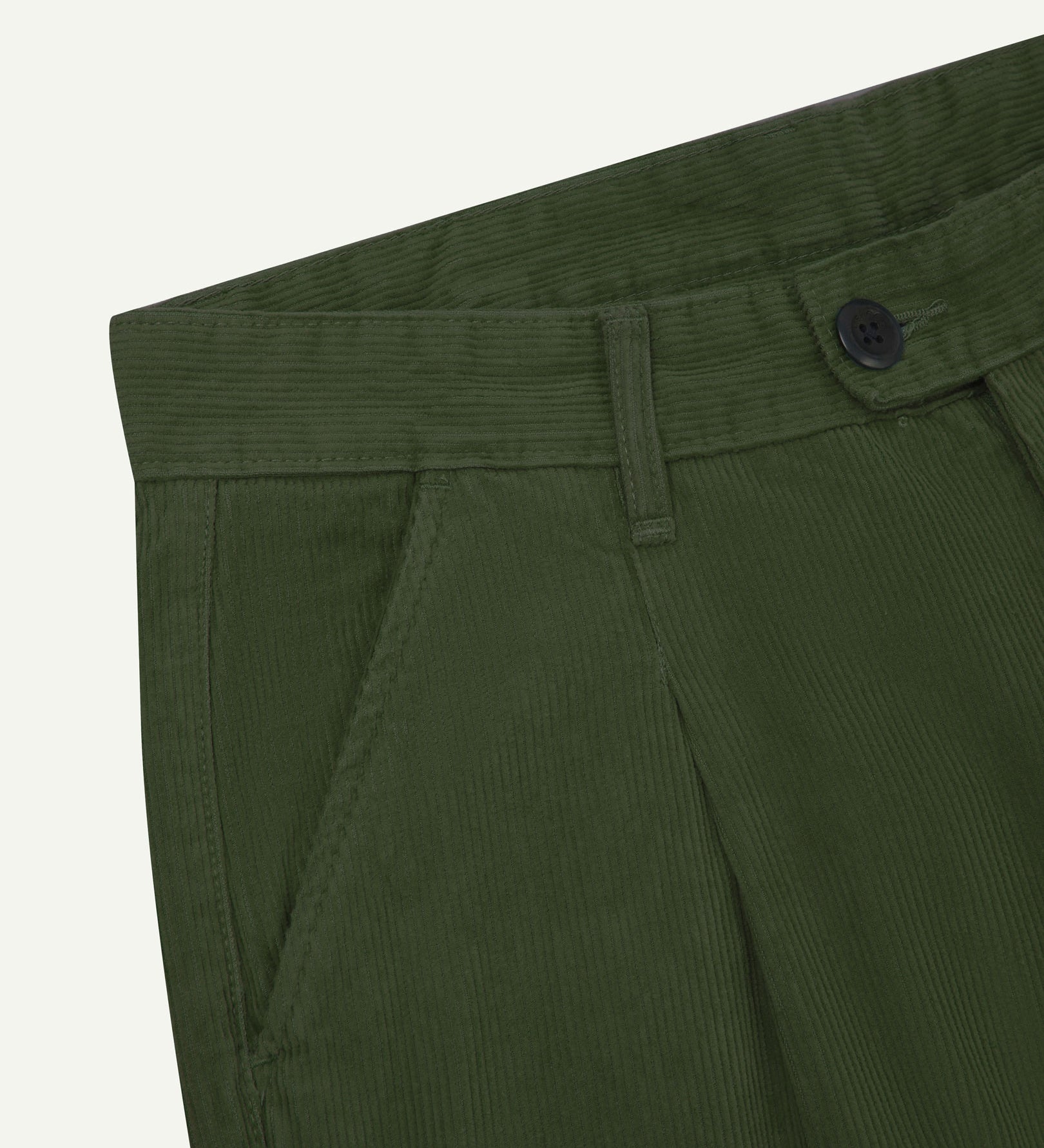 Close up of waist area of Uskees cord boat pants in coriander green. Clear view of front pocket, belt loops and Corozo button fastening.